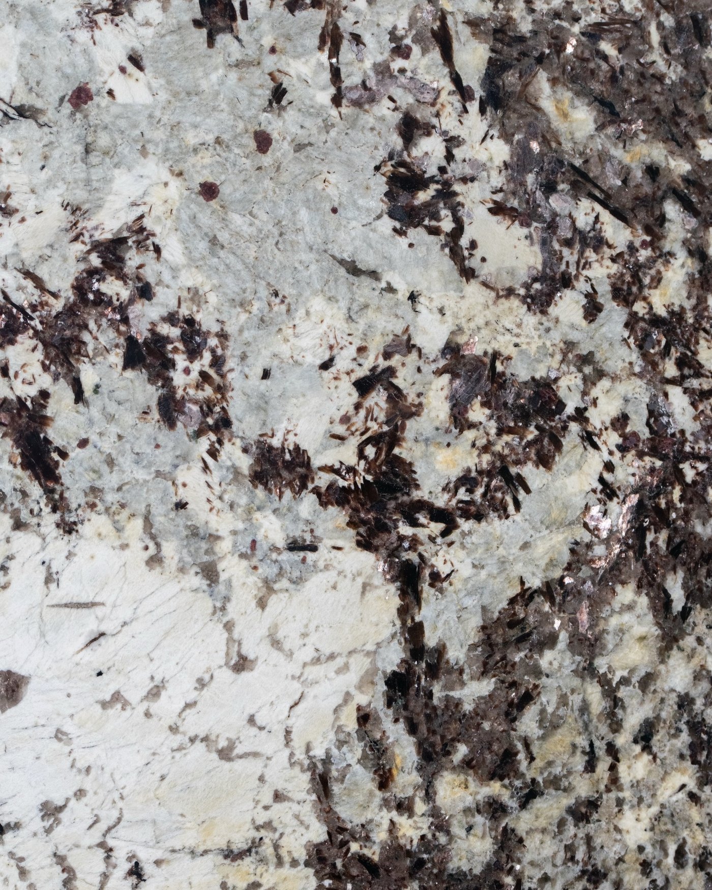 Close view of a polished slab surface, white ground with heavy burgundy and black crystalline veining