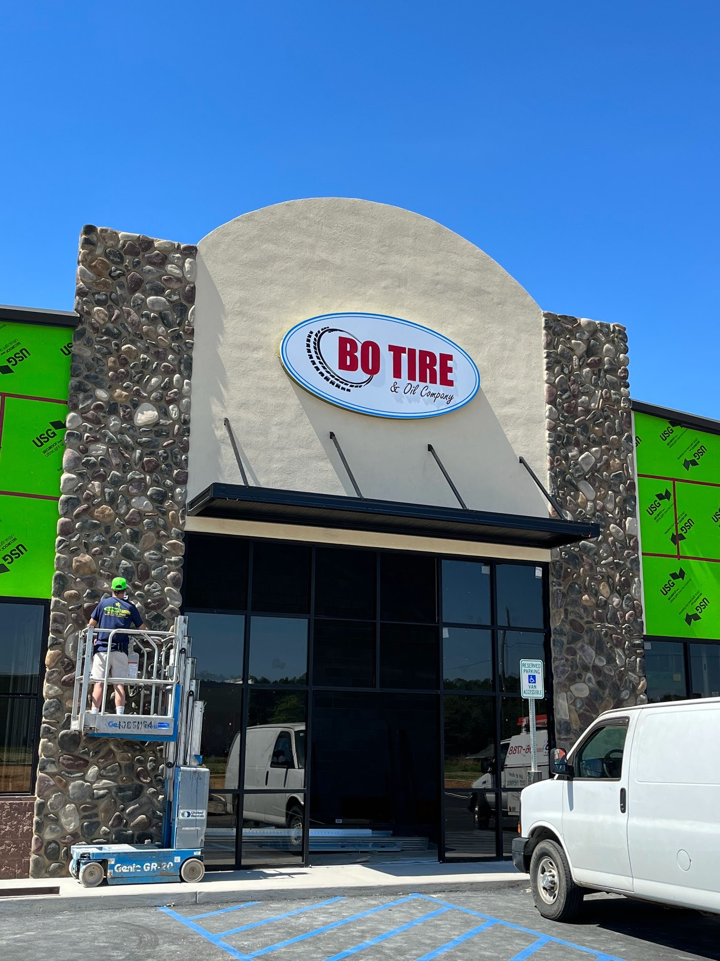 River-rock stone columns flanking the glass entrance of a commercial storefront still under construction
