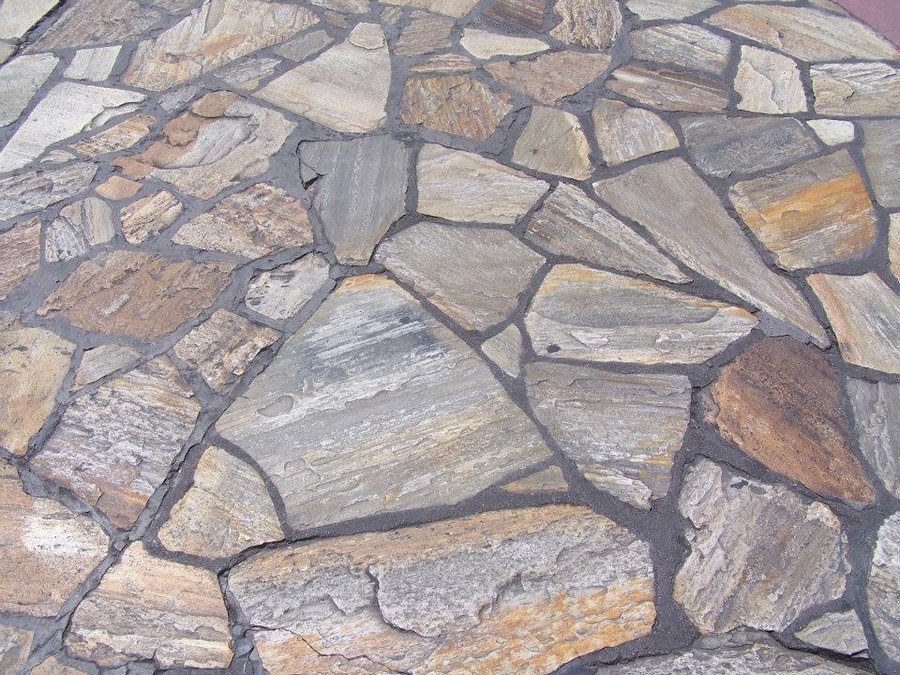 Close view of natural flagstone paving laid in irregular pieces with dark mortared joints