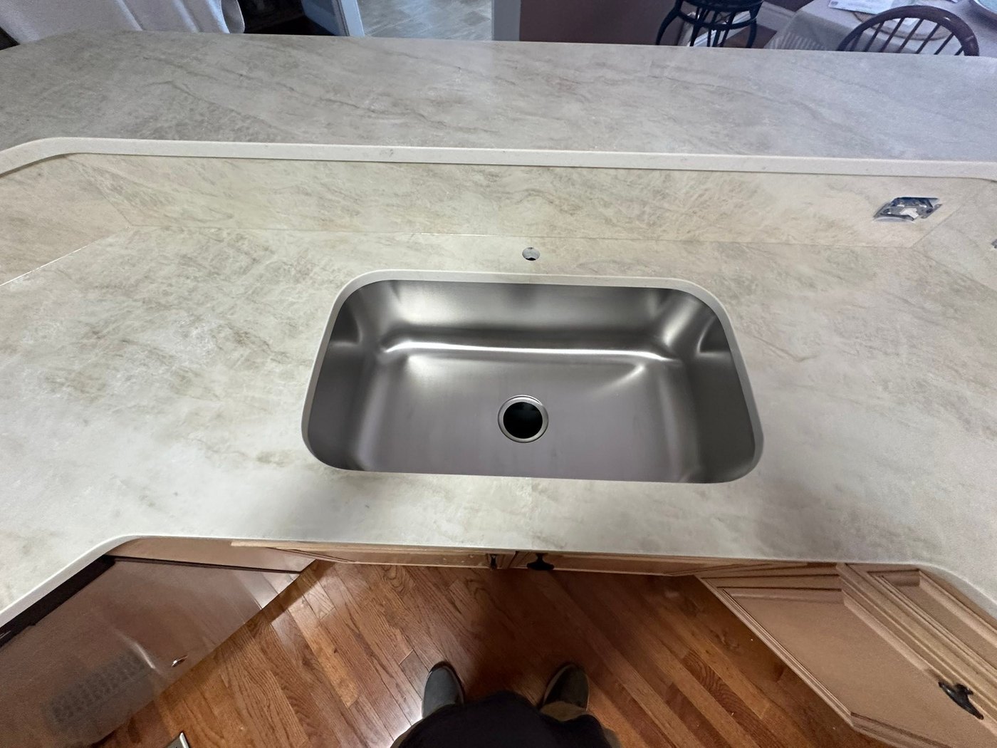 Overhead view of a pale veined stone kitchen counter with a large single-bowl stainless undermount sink and a rounded outside corner